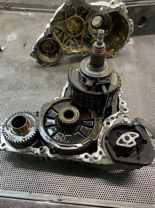 Rozebrana przekładnia lub skrzynia biegów z widocznymi kołami zębatymi i elementami wewnętrznymi.